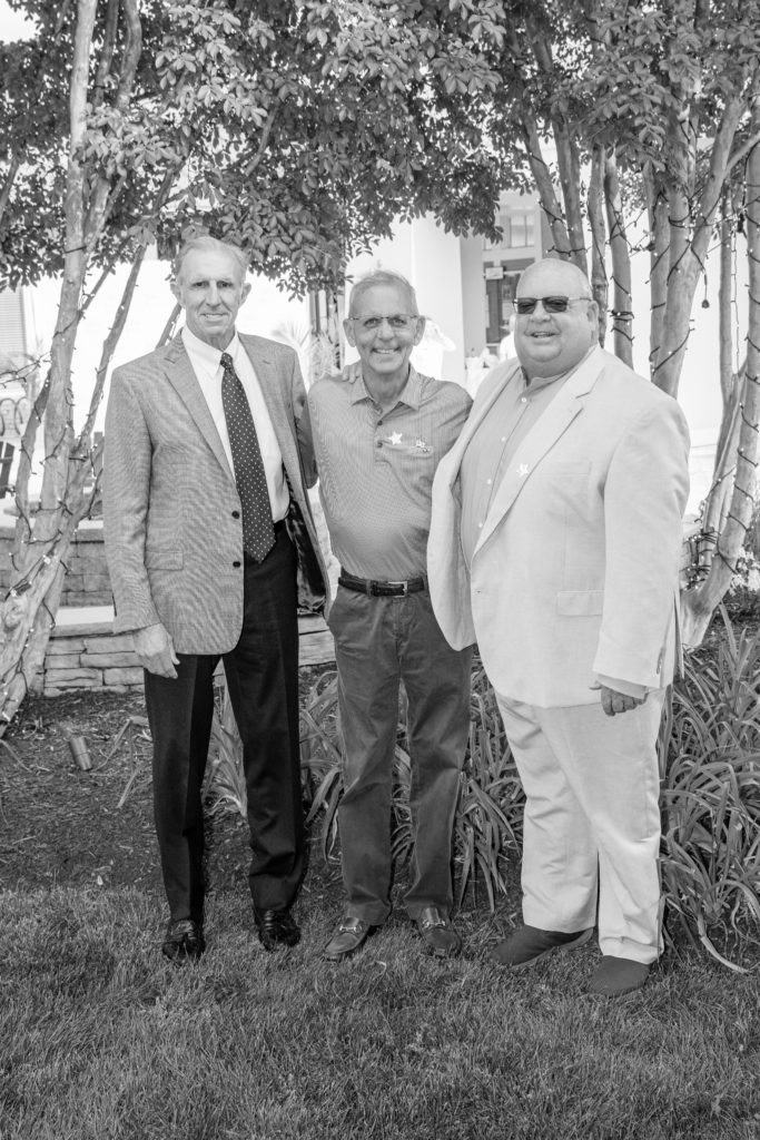 three men standing next to each other in the grass