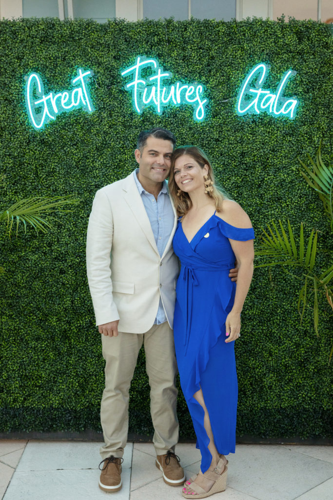 a man and woman standing in front of a green wall