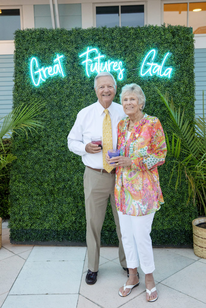 an older couple standing in front of a green wall