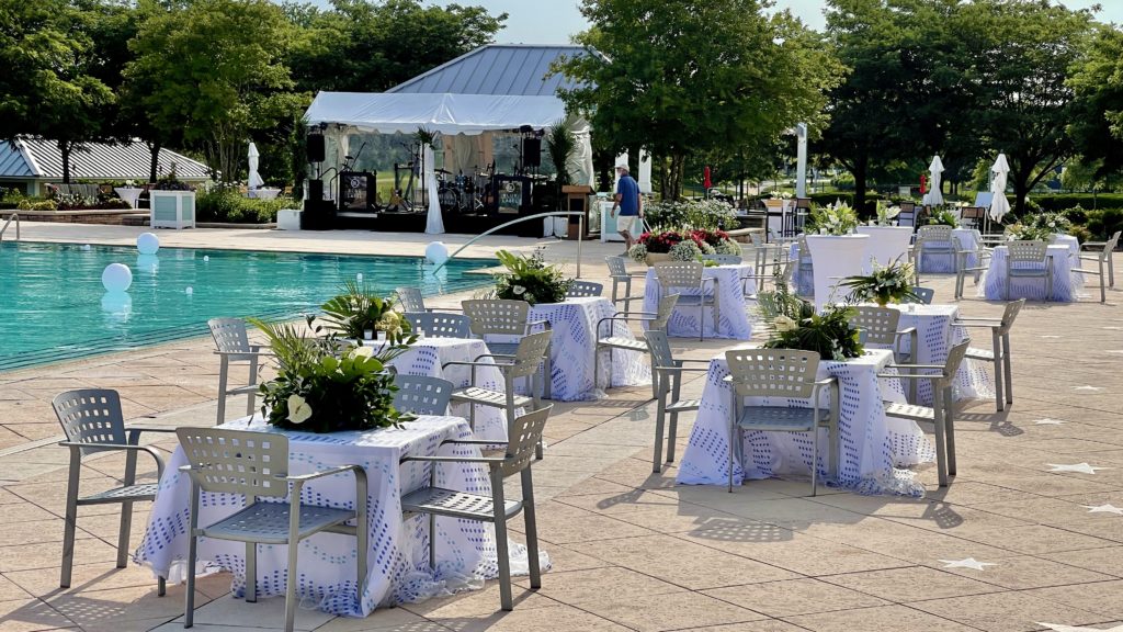 outdoor tables with white tablecloths and green center piece